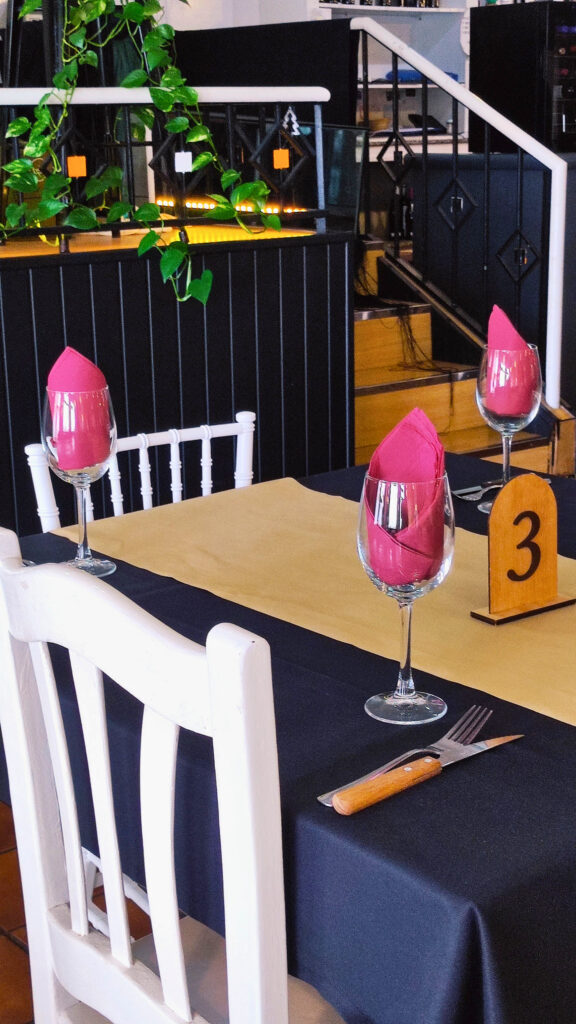 mesa en el comedor del asador Edan, copas de cristal con servilletas de color granate, mantel negro y al fondo