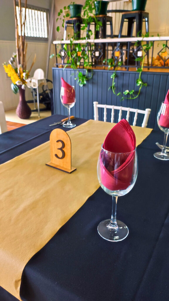 mesa en el comedor del asador Edan, copas de cristal con servilletas de color granate, mantel negro y al fondo decoración con plantas