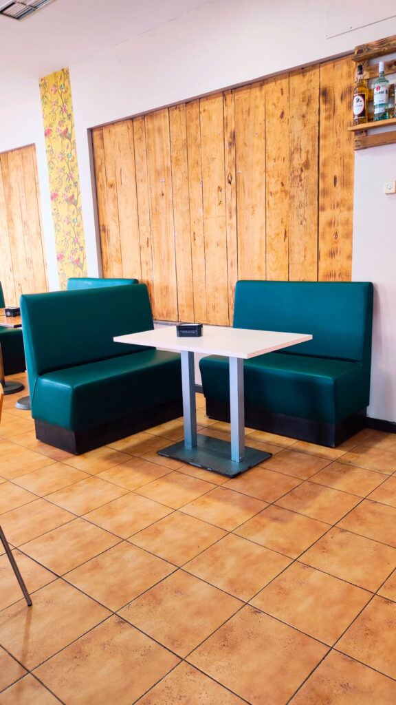 mesa blanca y sofás verdes en zona de cafetería del Asador Edan